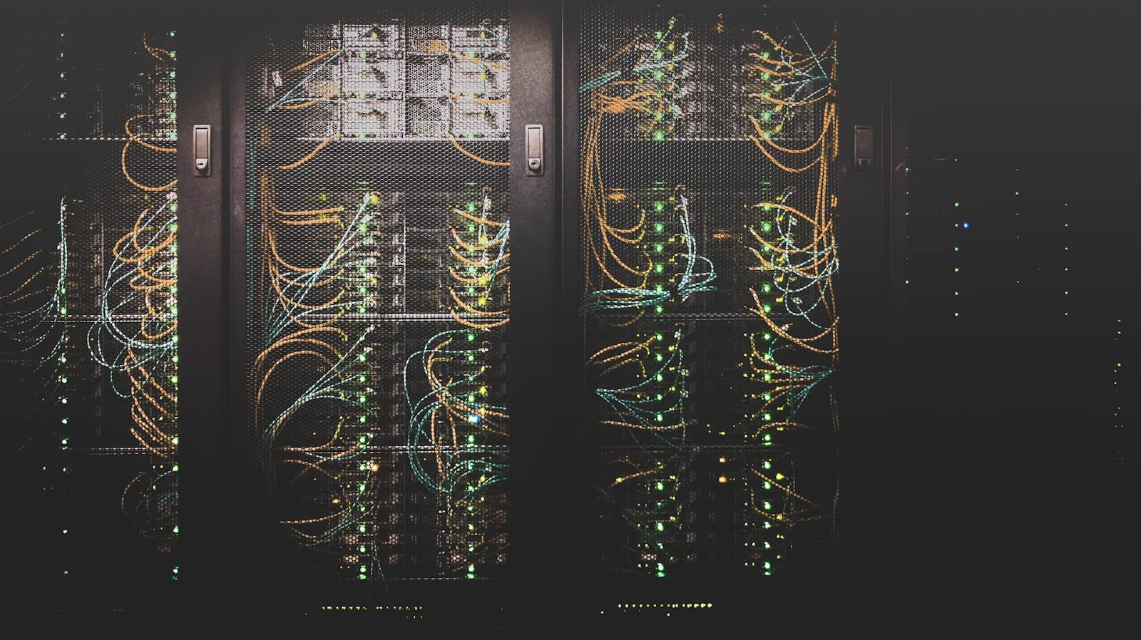 Baie de serveurs en datacenter avec câbles fibre et témoins lumineux dans une salle sombre
